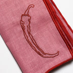 Pink fabric with embroidered chili pepper design on a white background