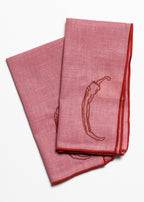 Two pink napkins with embroidered chili pepper design on a white background