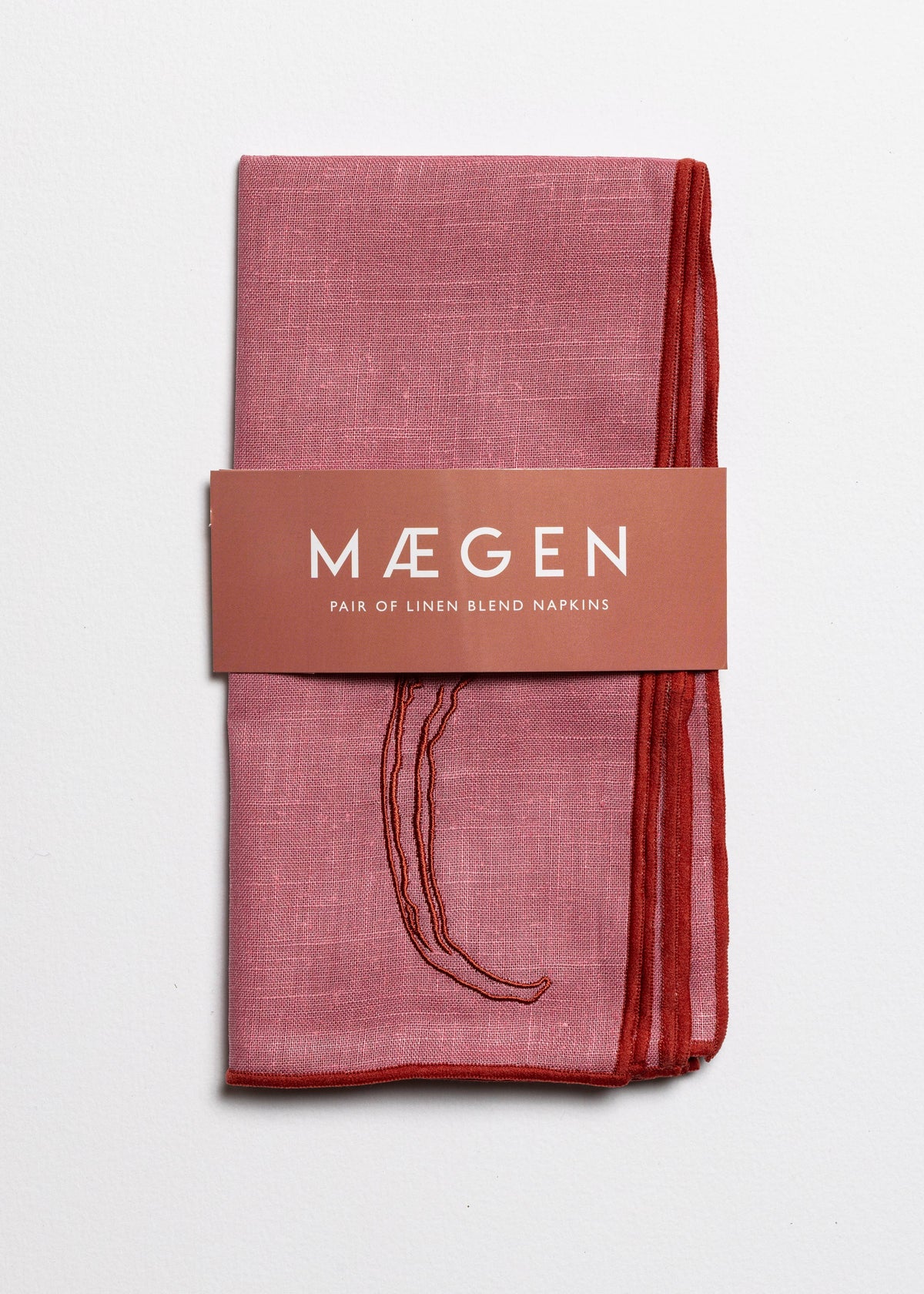 Packaged pink linen blend napkins with 'Máegen' branding on a light gray background